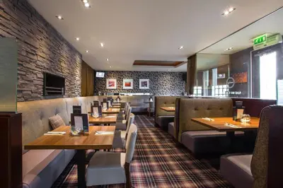 a restaurant with tables and chairs and a brick wall at The Parkville Hotel in Hamilton
