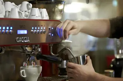 a person making a cup of coffee in a espresso machine at The Parkville Hotel in Hamilton