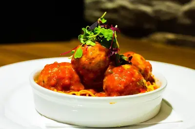 a bowl of food with meatballs and spaghetti on a plate at The Parkville Hotel in Hamilton