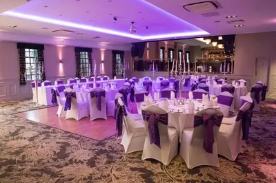 a banquet hall with white tables and purple chairs at The Parkville Hotel in Hamilton