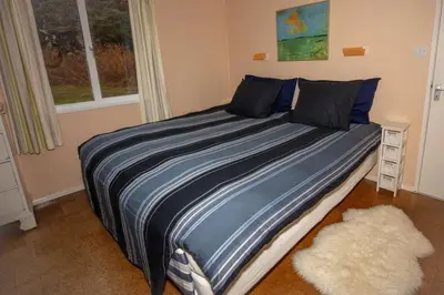 a bedroom with a bed with a blue blanket and a window at Ormsaig Wooden Cottage in Burgh