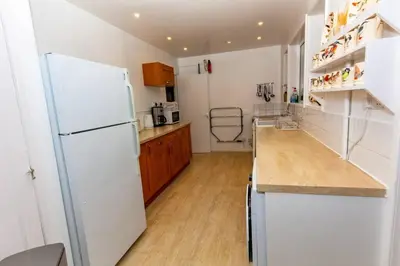 a kitchen with white appliances and a white refrigerator at Ormsaig Wooden Cottage in Burgh