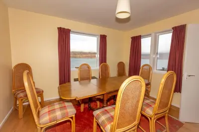a dining room with a wooden table and chairs at Ormsaig Wooden Cottage in Burgh
