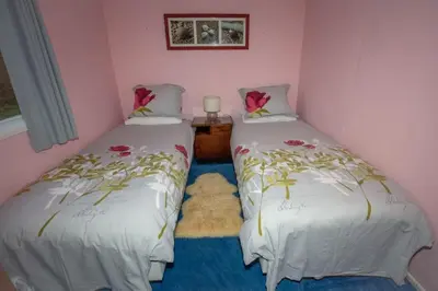 two twin beds in a room with pink walls at Ormsaig Wooden Cottage in Burgh