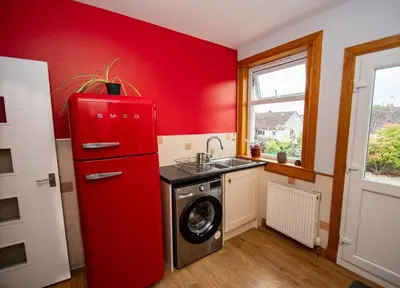 a red refrigerator in a kitchen with a washing machine at Linburn Cottage Dunfermline near Edinburgh in Dunfermline