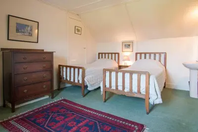 a bedroom with two beds and a dresser and a rug at Ardnadrochet Cottage in Lochdon