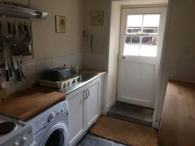 a kitchen with a washing machine and a door at Ardnadrochet Cottage in Lochdon