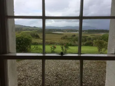 a window with a view of a field seen through it at Ardnadrochet Cottage in Lochdon
