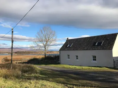 a white house sitting on the side of a road at Stable Cottage, Ardnadrochet in Lochdon