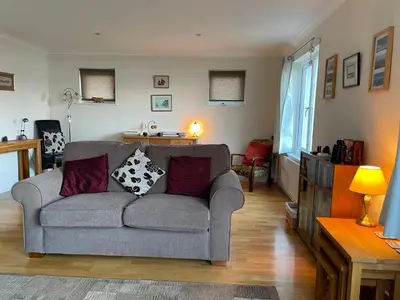 a living room with a gray couch with pillows at The Cottage, overlooking Loch Fyne in Cairndow