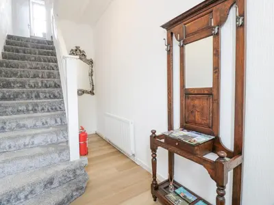 a hallway with stairs and a mirror and a table at Little Ireland in Stranraer