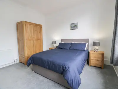 a bedroom with a blue bed and a wooden cabinet at Little Ireland in Stranraer