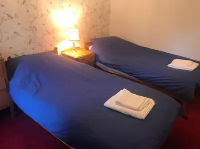 two beds in a room with blue sheets and white towels at Barrachandroman Farmhouse in Lochbuie