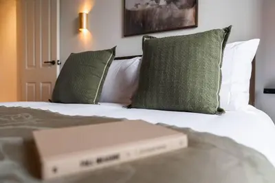 a book sitting on top of a bed with pillows at The West End Retreat - Your Luxurious 5* Apartment in Glasgow