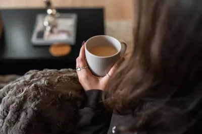 a woman is holding a cup of coffee at The West End Retreat - Your Luxurious 5* Apartment in Glasgow