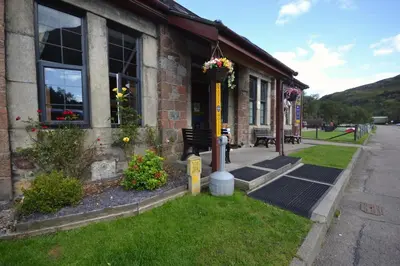 a building with a bench and flowers outside of it at Blackwater Hostel in Kinlochleven