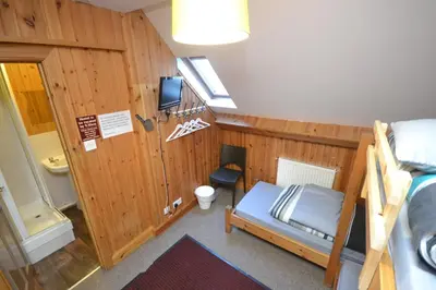 a small room with a bunk bed and a bathroom at Blackwater Hostel in Kinlochleven