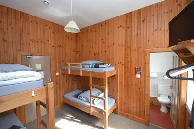 a bedroom with a bed and a desk and a bunk bed at Blackwater Hostel in Kinlochleven