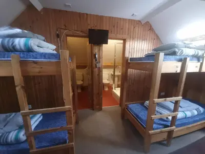 a room with three bunk beds and a bathroom at Blackwater Hostel in Kinlochleven