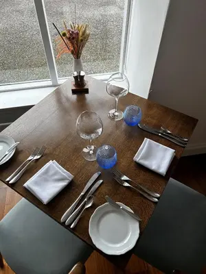 a wooden table with plates and glasses and silverware at The Airds Hotel and Restaurant in Port Appin