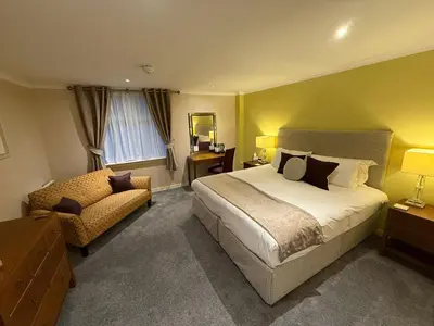 a bedroom with a large bed and a chair at The Airds Hotel and Restaurant in Port Appin