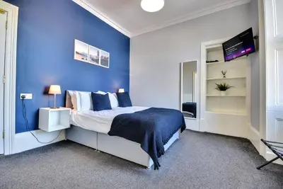 a blue bedroom with a bed and a tv at Exclusive Use in Gourock