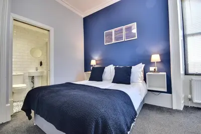 a bedroom with a large bed with a blue wall at Exclusive Use in Gourock