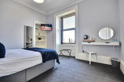 a white bedroom with a bed and a mirror at Exclusive Use in Gourock