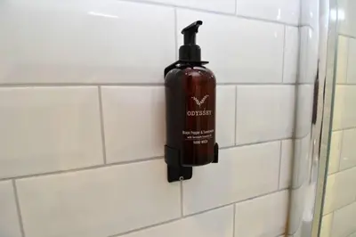 a bottle of soap is hanging on a tiled wall at The Shore in Gourock