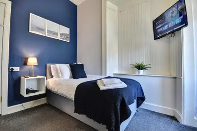 a bedroom with a bed with blue walls and a tv at The Cove in Gourock