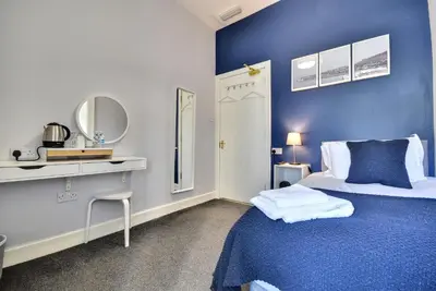 a blue and white bedroom with a bed and a mirror at The Cove in Gourock