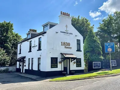 a white building on the corner of a street at The Cloch in Gourock