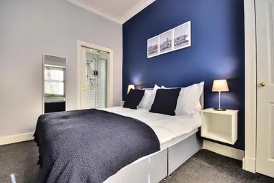 a bedroom with a large bed with a blue wall at The Kempock in Gourock
