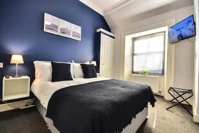 a blue bedroom with a bed and a window at The Kempock in Gourock