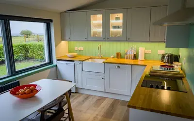 a kitchen with white cabinets and a bowl of fruit on a table at Croft 11 Clovullin in Ardgour