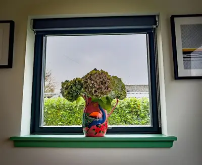 a vase with flowers sitting on a window sill at Croft 11 Clovullin in Ardgour