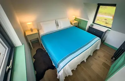 a small room with a bed and two tables and a window at Croft 11 Clovullin in Ardgour