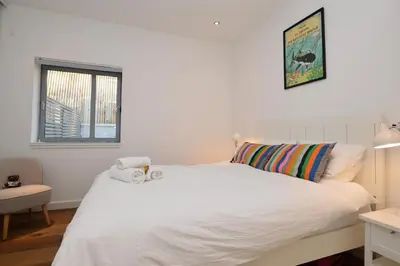 a bedroom with a white bed and a window at Old Fire Station in Tighnabruaich