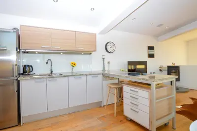 a kitchen with white cabinets and a stainless steel refrigerator at Old Fire Station in Tighnabruaich
