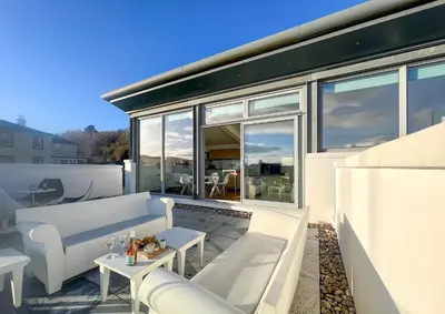 a patio with white furniture and large windows at Old Fire Station in Tighnabruaich