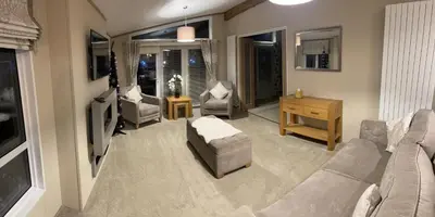a living room with a couch and chairs and a tv at Loubet Extra Large Lodge in Auchterarder