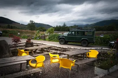 a group of yellow chairs and picnic tables and a green jeep at MHOR 84 in Kingshouse