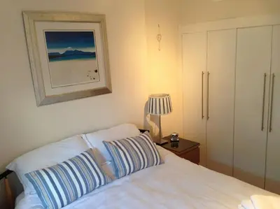 a bedroom with a bed and a picture on the wall at Millport Beach Apartment, Crichton St, sea views in Millport