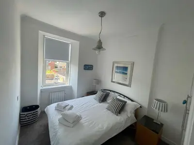 a bedroom with a white bed and a window at Millport Beach Apartment, Crichton St, sea views in Millport