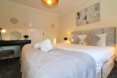 a bedroom with a large white bed and a desk at Signature - Shield House in Scotstoun