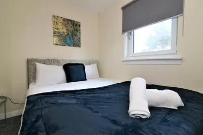 a bedroom with a bed with white sheets and a window at Signature - Shield House in Scotstoun