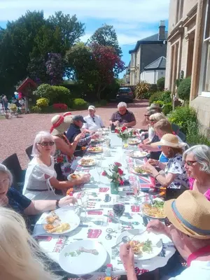 a group of people sitting at a long table eating food at Moorlands in Helensburgh