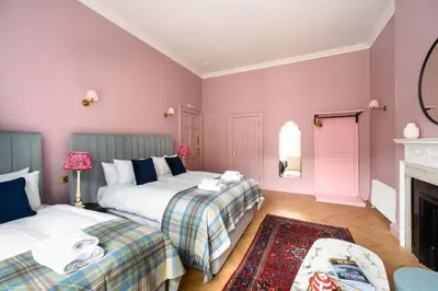 a bedroom with two beds and a fireplace at Queen Charlotte Guesthouse in Edinburgh