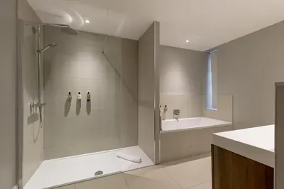 a bathroom with a shower and a tub and a sink at Destiny Scotland - Hill Street Apartments in Edinburgh