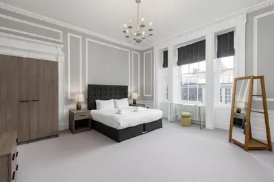 a white bedroom with a bed and a chandelier at Destiny Scotland - Hill Street Apartments in Edinburgh